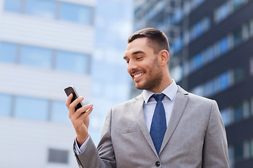 Image showing smiling businessman with smartphone outdoors