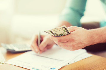 Image showing close up of man counting money and making notes