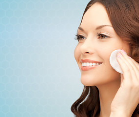 Image showing smiling woman cleaning face skin with cotton pad