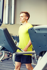 Image showing man with smartphone exercising on treadmill in gym