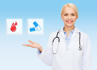 Image showing smiling doctor or nurse pointing to pills icon