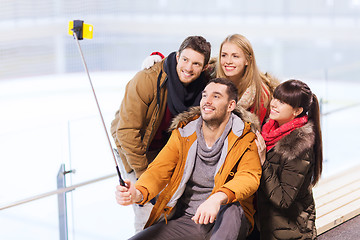 Image showing happy friends with smartphone on skating rink