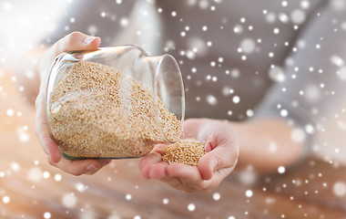 Image showing close up of female emptying jar with quinoa