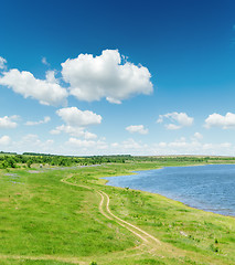 Image showing green landscape with road and pond under blue sky with white clo