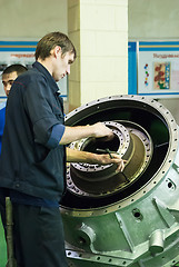 Image showing Mechanic assembles part for aviation engine