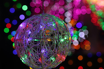 Image showing Christmas wire mesh bauble and coloured backgound of defocused l