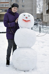 Image showing The woman near a snowman in the yard of the house.