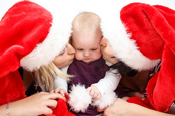 Image showing two womans with santa hat kissing baby