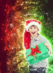 Image showing happy boy in santa hat surprised by christmas present