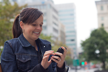 Image showing Woman texting with her smart phone outside in the city