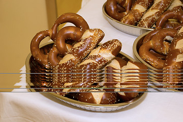 Image showing Laugen pretzels and sticks in bowls on a table with white tablec