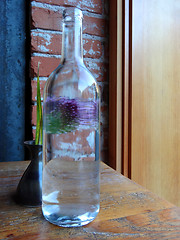 Image showing Still-life of a bottle and a flower in a vase