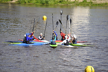 Image showing People on kayaks lifted oars up.