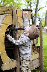 Image showing 2 years old curious Baby boy managing with old agricultural Mach