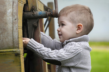 Image showing 2 years old curious Baby boy managing with old agricultural Mach