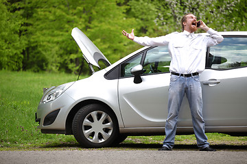 Image showing Driver furious with mobile phone a broken car by the road