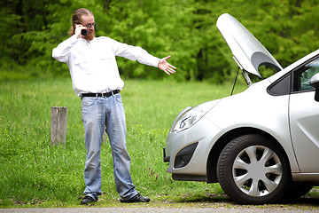 Image showing Driver furious with mobile phone a broken car by the road