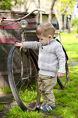 Image showing 2 years old curious Baby boy walking around the old bike 