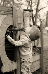 Image showing 2 years old curious Baby boy managing with old agricultural Mach