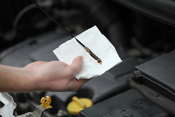 Image showing Auto mechanic checking engine oil dipstick in car