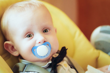 Image showing Pretty Baby Boy Sitting In Yellow Seat With Soother