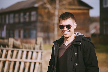 Image showing Young Handsome Man Staying Near Old Wooden House In Autumn Or Sp