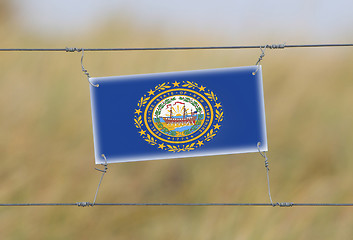 Image showing Border fence - Old plastic sign with a flag