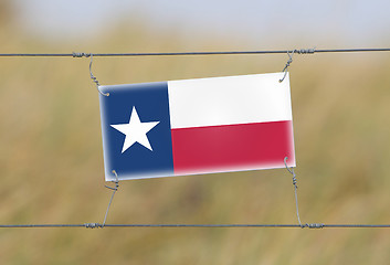 Image showing Border fence - Old plastic sign with a flag