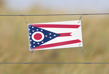 Image showing Border fence - Old plastic sign with a flag