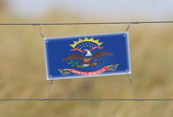 Image showing Border fence - Old plastic sign with a flag