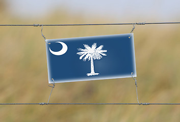 Image showing Border fence - Old plastic sign with a flag