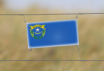 Image showing Border fence - Old plastic sign with a flag