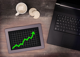 Image showing Tablet touch computer gadget on wooden table, graph positive