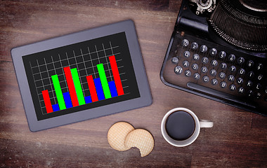 Image showing Tablet touch computer gadget on wooden table, graph