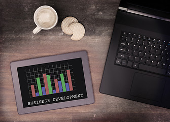 Image showing Tablet touch computer gadget on wooden table, graph