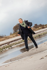 Image showing Happy senior woman frolicking on the beach