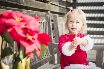 Image showing Adorable Little Girl Sitting On Bench with Her Candy Cane