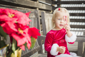 Image showing Adorable Little Girl Sitting On Bench with Her Candy Cane