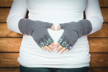 Image showing Pregnant Woman Holds Her Stomach with Love You Mittens