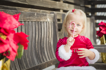 Image showing Adorable Little Girl Sitting On Bench with Her Candy Cane