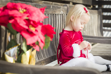 Image showing Adorable Little Girl Sitting On Bench with Her Candy Cane