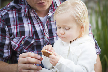 Image showing Adorable Little Girl Eating a Cookie with Daddy