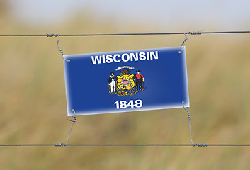 Image showing Border fence - Old plastic sign with a flag