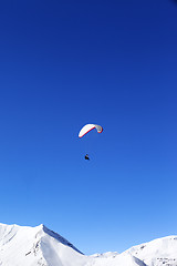 Image showing Paraglider in snowy winter mountains at sun day