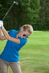 Image showing Young woman golf player on course doing golf swing