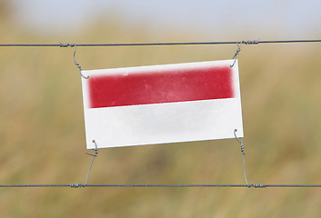 Image showing Border fence - Old plastic sign with a flag