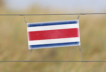 Image showing Border fence - Old plastic sign with a flag