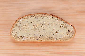 Image showing Slice of buttered bread on a wooden table