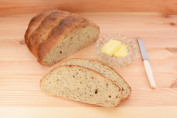 Image showing Fresh bread with butter and knife on a wooden table