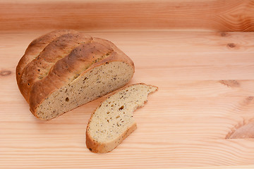 Image showing Half-eaten loaf of bread on a table with a cut slice